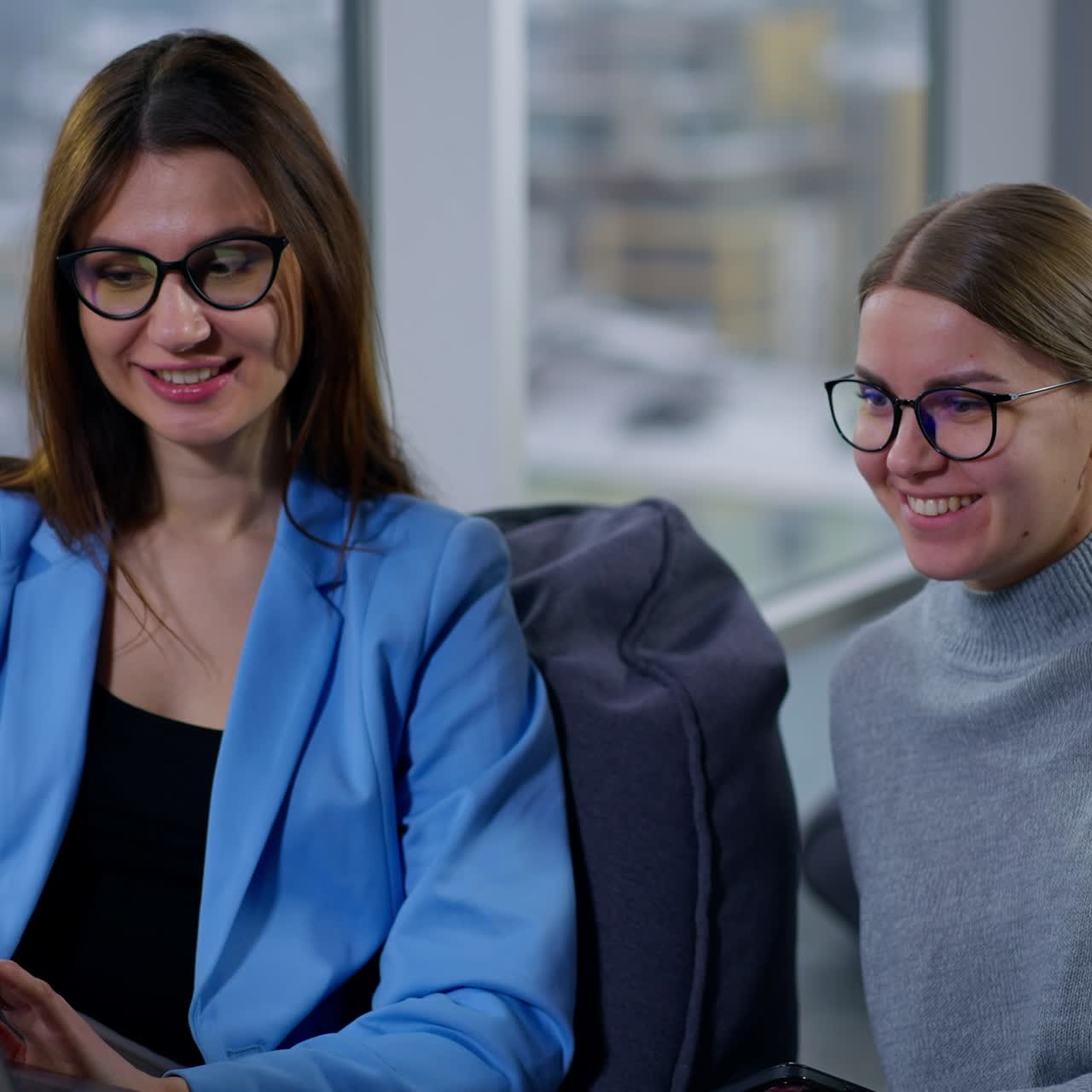 Smiling female colleagues look satisfactory at the screen of the laptop. Ladies looking thorough the files or images commenting and discussing them
