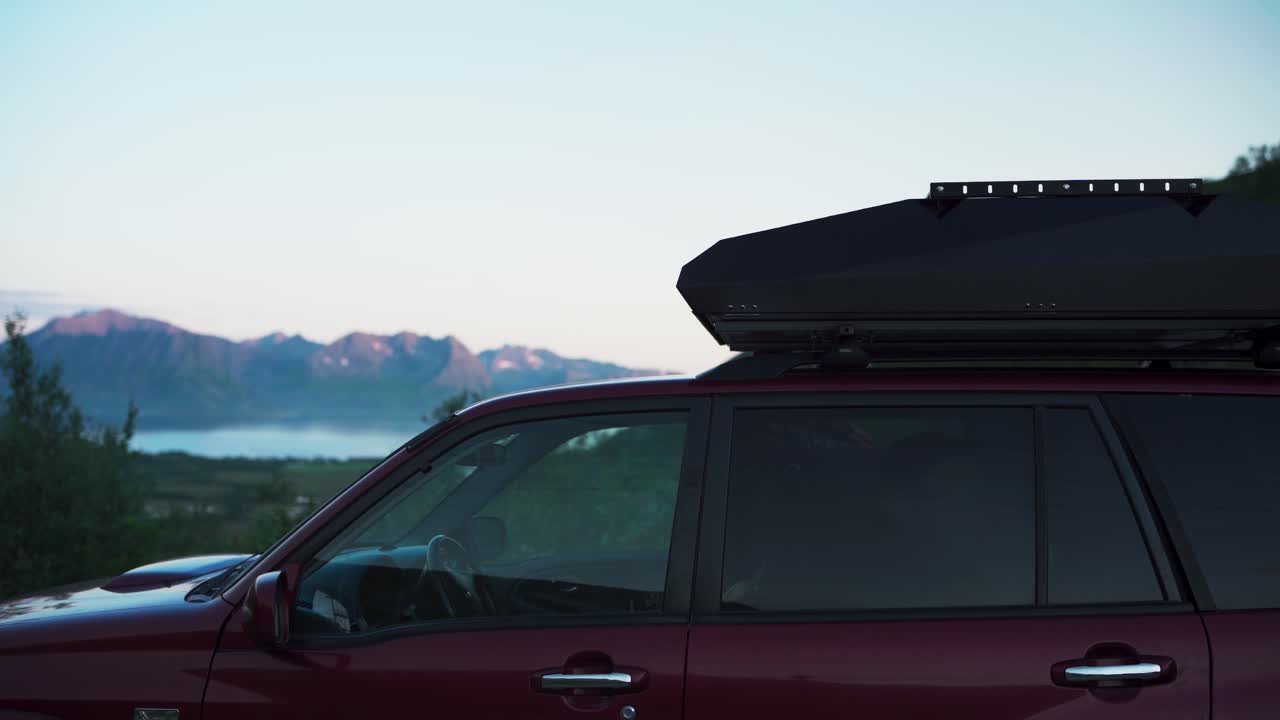 피오르드 근처 에 주차 되어 있는 캠핑카 에 지붕 에 텐트 를 준비 하는 사람