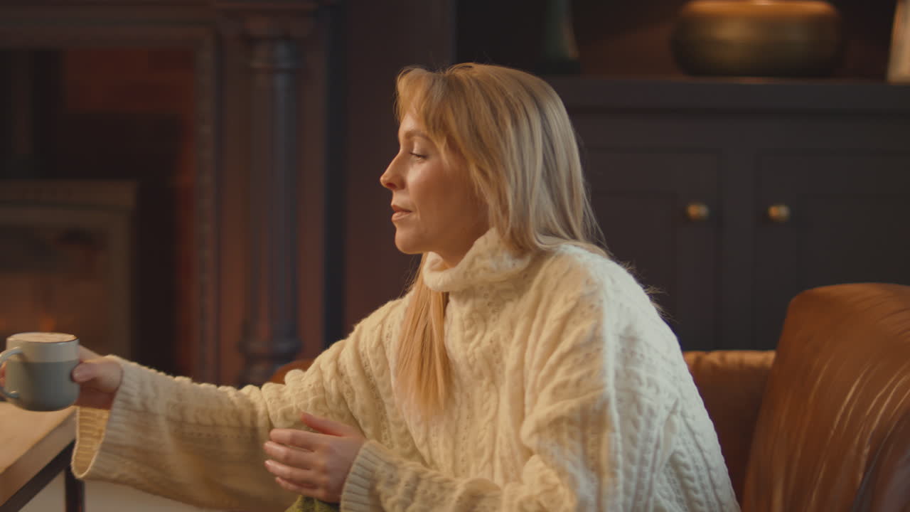 뜨거운 음료와 함께 쾌적한 불과 함께 라운지에서 집에있는 여성