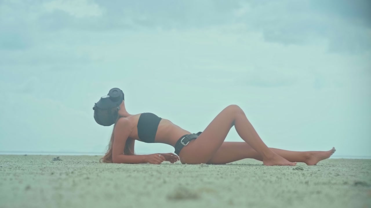 Donna con maschera antigas che si rilassa su una spiaggia sabbiosa