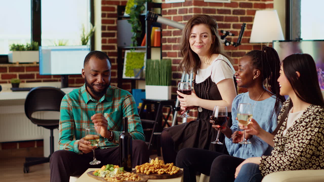 Portrait of happy friends having entertaining conversation, eating snacks from charcuterie board at home