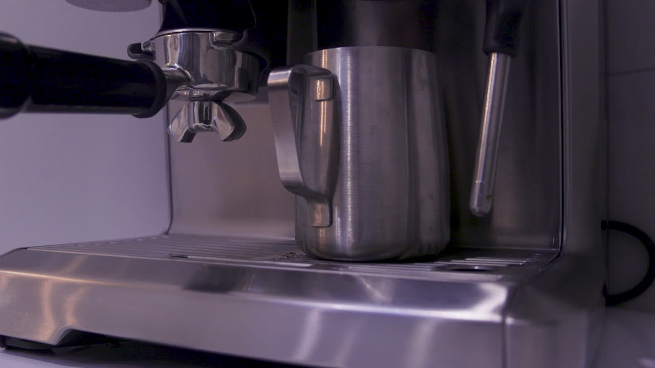 A close-up of a coffee machine in action, showcasing the brewing process of a rich espresso. The sleek design enhances the modern kitchen ambiance, creating a warm, inviting atmosphere