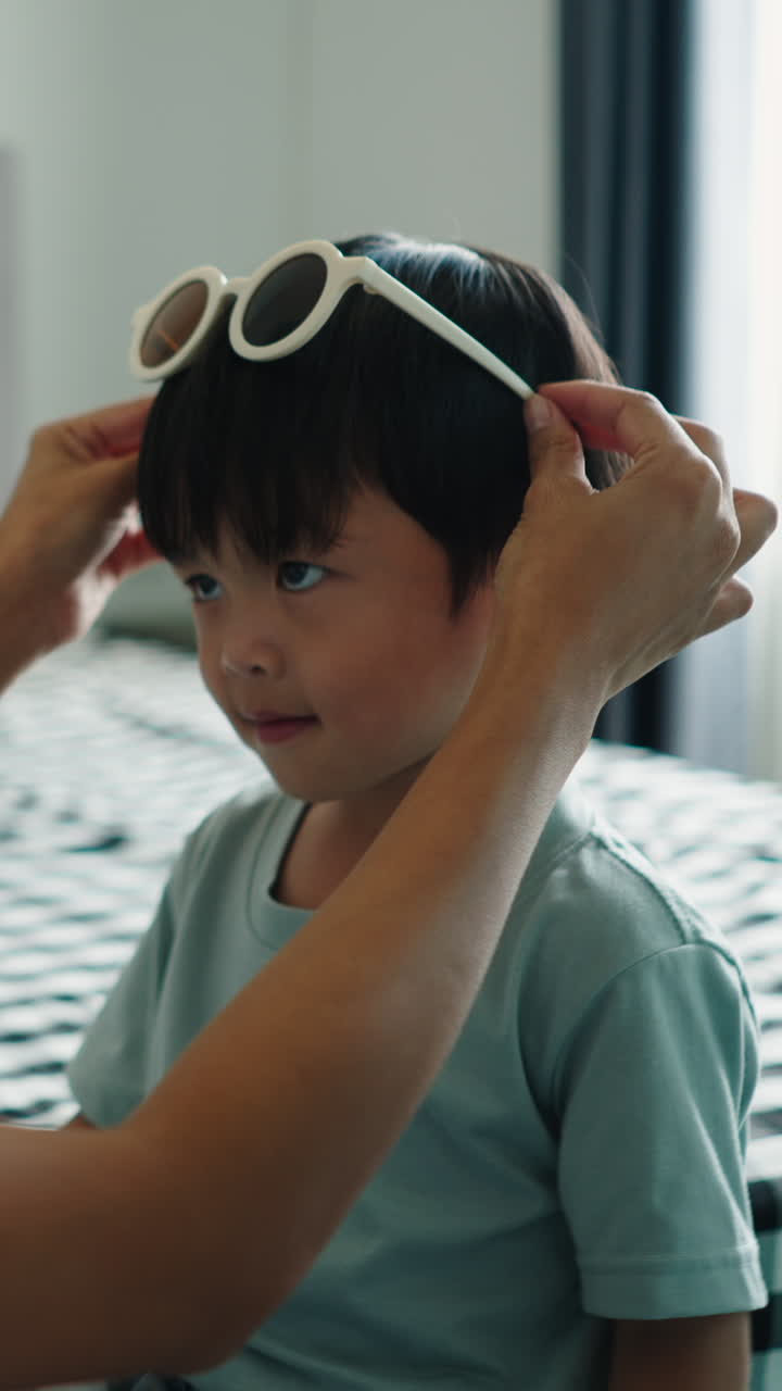 Bambino carino che gioca con gli occhiali da sole in casa