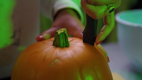 close up of pumpkin being carved in green light indoor slowmotion