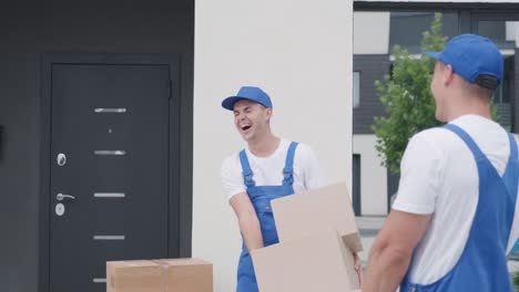 dos jóvenes trabajadores de una compañía de mudanzas entregan cajas a la casa de un cliente