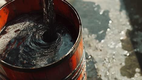 pouring dark liquid into a wooden bucket