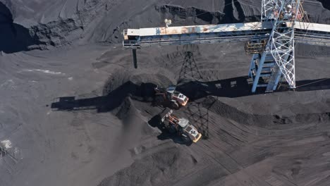 Wheel-Loaders-Working-And-Transporting-Coal-Under-Conveyor-Tower-In-Barahona,-Dominican-Republic