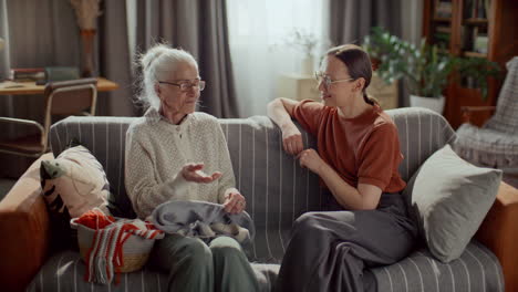 elderly woman sharing story with young granddaughter on couch at home