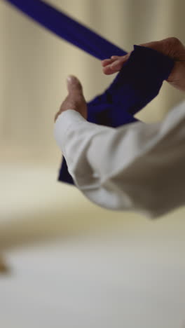 vertical video close up studio shot of two sikh men folding fabric for turban against plain background