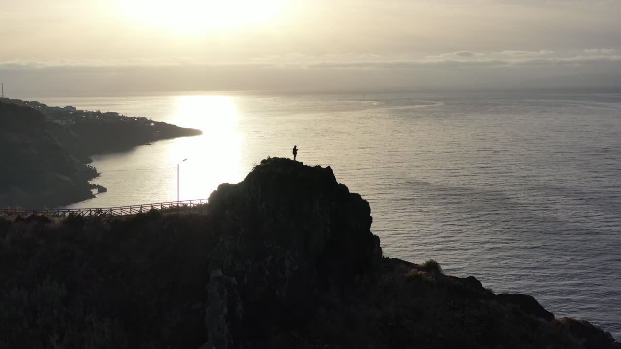 Aerial View, Silhouette of Lonely Person Standing Atop of Cliff Above Atlantic Ocean and Scenic Coastline of Madeira Island, Portugal on Golden Hour Sun at Horizon