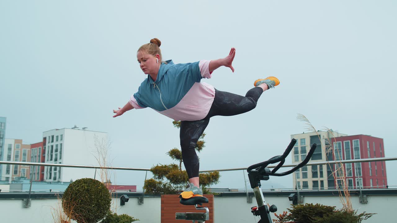 mujer atlética realizando una trampa de entrenamiento acrobático en una bicicleta estacionaria giratoria