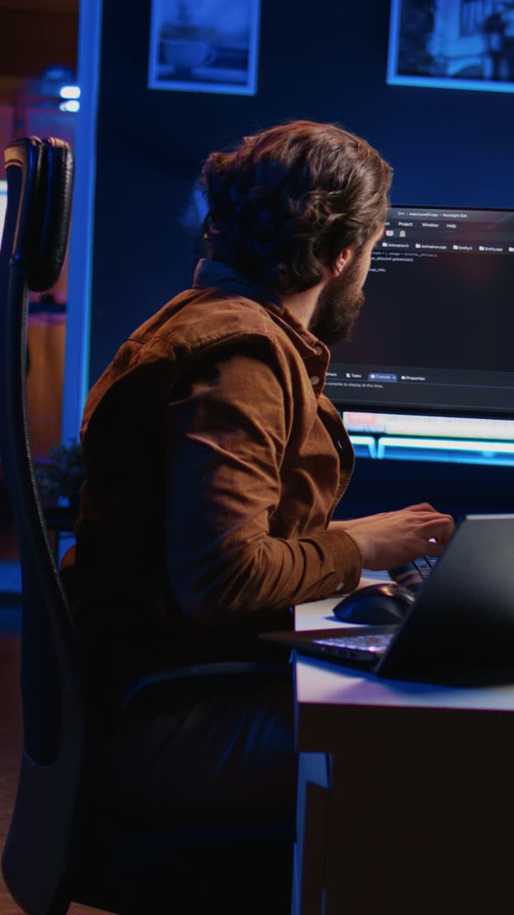 Focused Programmer Working Late Night on Laptop and Monitor