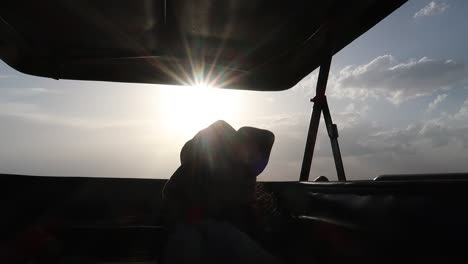 travel woman enjoying the sunset in 4x4 car through the african savanna