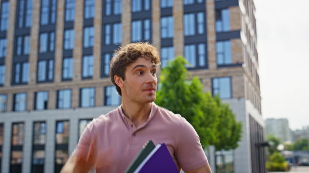 Cheerful man walking street holding books closeup. Smiling guy waving hand