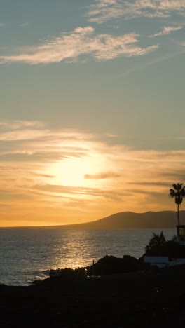 sunset over the ocean with mountains and palm trees