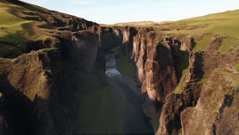 aerial: reverse reveal of the fjadrargljufur winding river canyon in southern iceland off the ring road