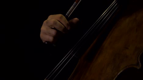 close-up of cellist playing pizzicato notes with bow in hand.