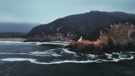 drone view of la peña blanca beach, mexico with powerful waves crashing on rocky shore and golden sand. manzanillo, colima state