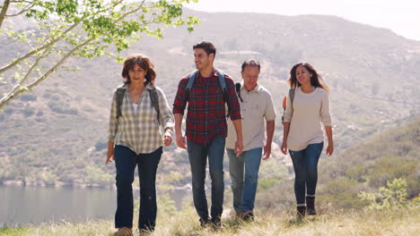 Young-couple-and-senior-parents-walking-in-mountains-by-lake