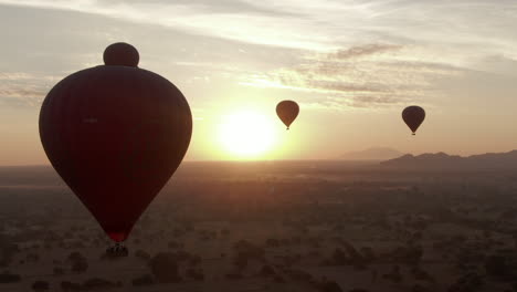 Primer-Plano-De-Un-Dron-Que-Muestra-La-Silueta-De-Globos-Aerostáticos-Contra-El-Amanecer-Dorado-En-Bagan,-Myanmar