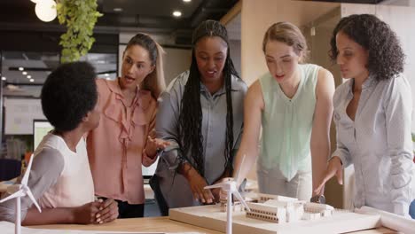 diverse team of happy female architects discussing architectural model at work, in slow motion