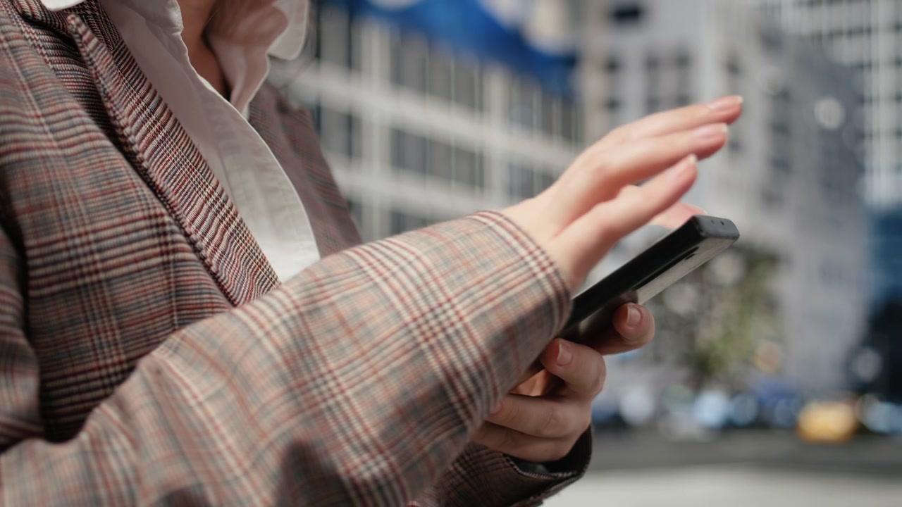 Primissimo piano di smartphone nelle mani di un professionista, con sfondo urbano.