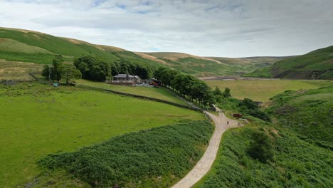 Imágenes-Aéreas-De-Drones-De-Los-Páramos-De-Los-Valles-Del-Campo-De-Yorkshire-Y-Moviéndose-Lentamente-Por-Un-Sendero-Hacia-Una-Granja