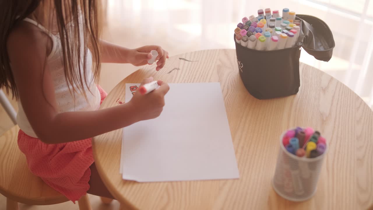A child drawing on a table with markers