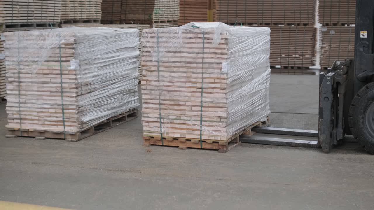Forklift Backs Away from Pallet of Wrapped Lumber in Warehouse