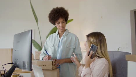 two women working in office, checking stock inventory and talking with client