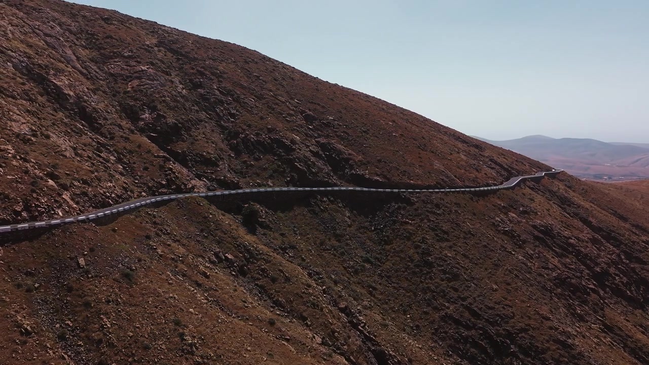 Strada sinuosa lungo un pendio montano in un paesaggio desertico.
