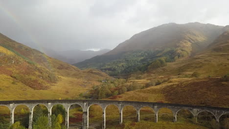 Aerial:-Rainbow-arcs-over-curved-Glenfinnan-Viaduct-train-bridge