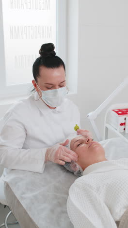 beautician applying special moisturizing cream scrub chemical peeling face of pretty woman girl