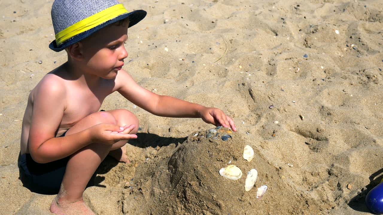 장난감으로 놀고 해변에 모래 성을 짓는 재미있는 소년.