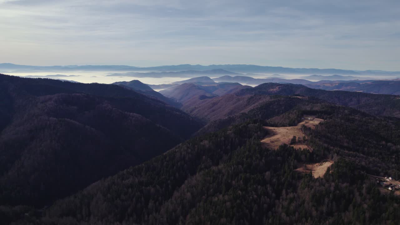 vista aérea de un valle con montañas rodeadas de smog en el fondo