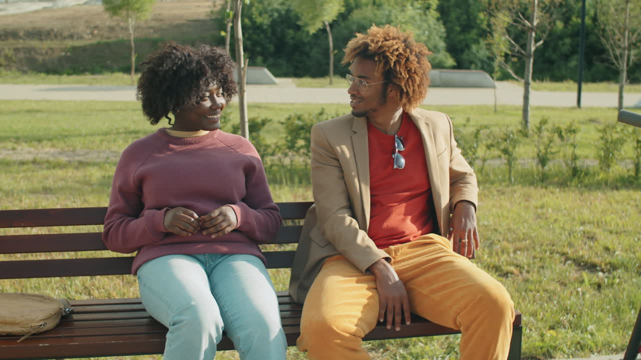 African American Man and Woman Speaking on Bench in Park