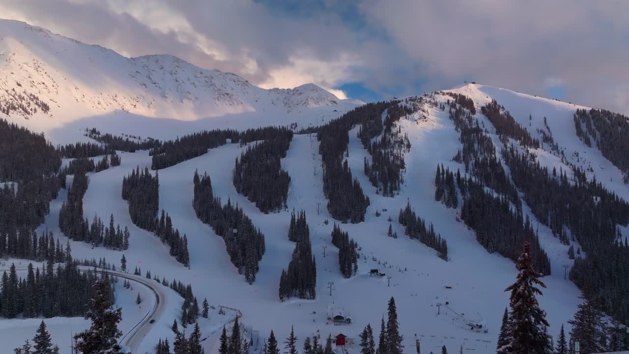 Loveland Pass sunset Arapahoe Basin Basin Abay Ski Resort Colorado aerial drone winter spring last light golden hour groomed ski trail runs chairlift main lodge Base Area parking lot upwards motion