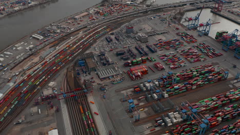 Aerial-view-of-large-cargo-container-terminal-in-Hamburg-with-reveal-of-the-river-and-city-industrial-district