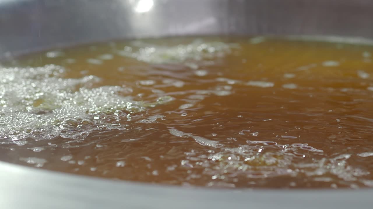 Golden Broth Simmering with Bubbles in a Metal Pot