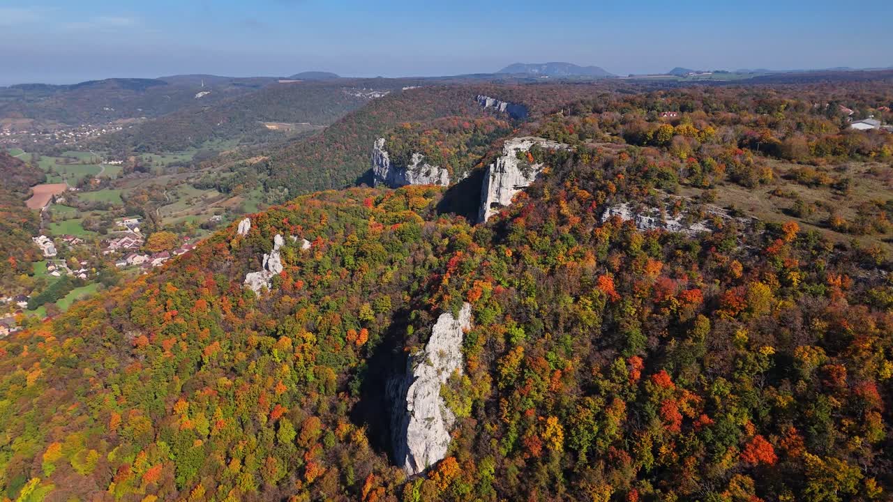 Aerial view of Cirque du Fer à Cheval in France featuring dramatic limestone cliffs surrounded by vibrant autumn forests, rugged terrain, distant hills and a vast natural landscape