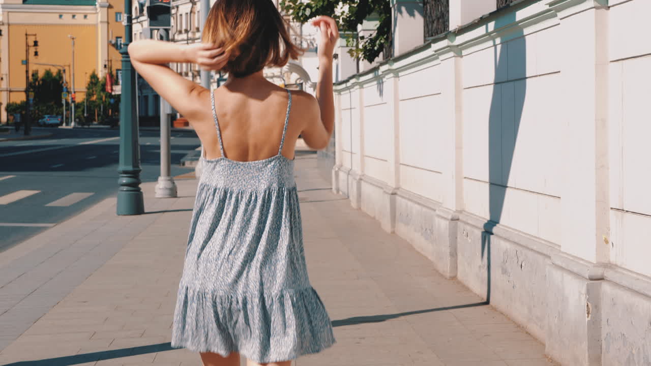 인쇄 된 드레스 를 입고 도시 거리 를 고 있는 여자