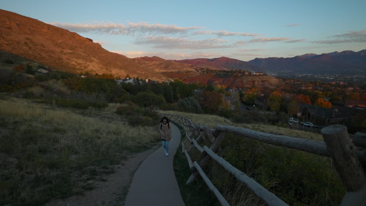 una mujer camina por un sendero pavimentado cerca de salt lake city, utah al atardecer con montañas pintorescas.