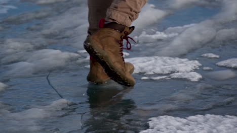 slow-motion shot of the boots of a person walking on ice