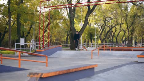 slow motion shot of a hipster skateboarder jumping on the pipe in the skatepark. tries not to fall in the end