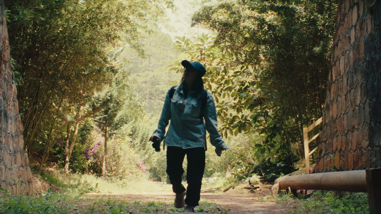 Silhouette of a person hiking in a forest taking a picture with their mobile phone
