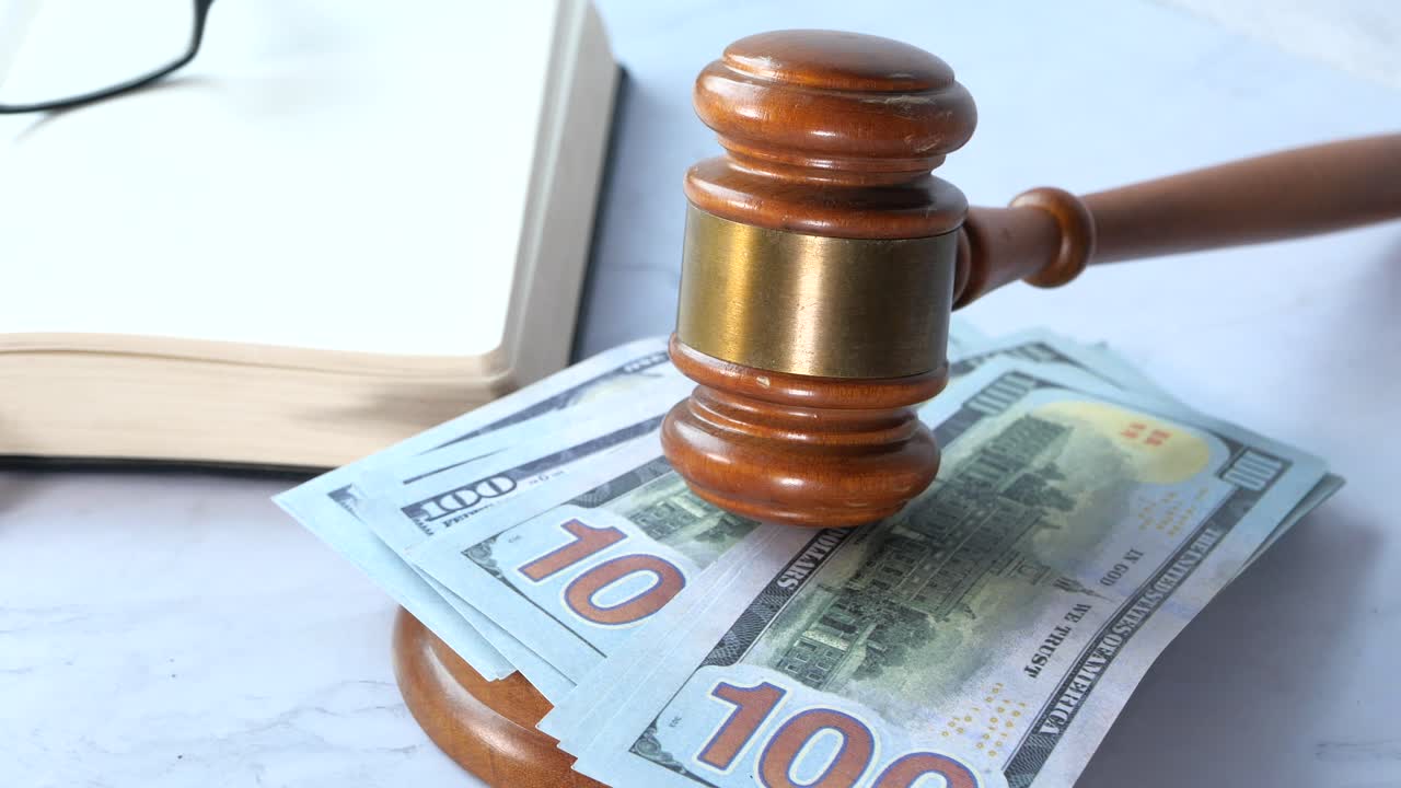 Gavel resting on US dollar bills with a book in the background