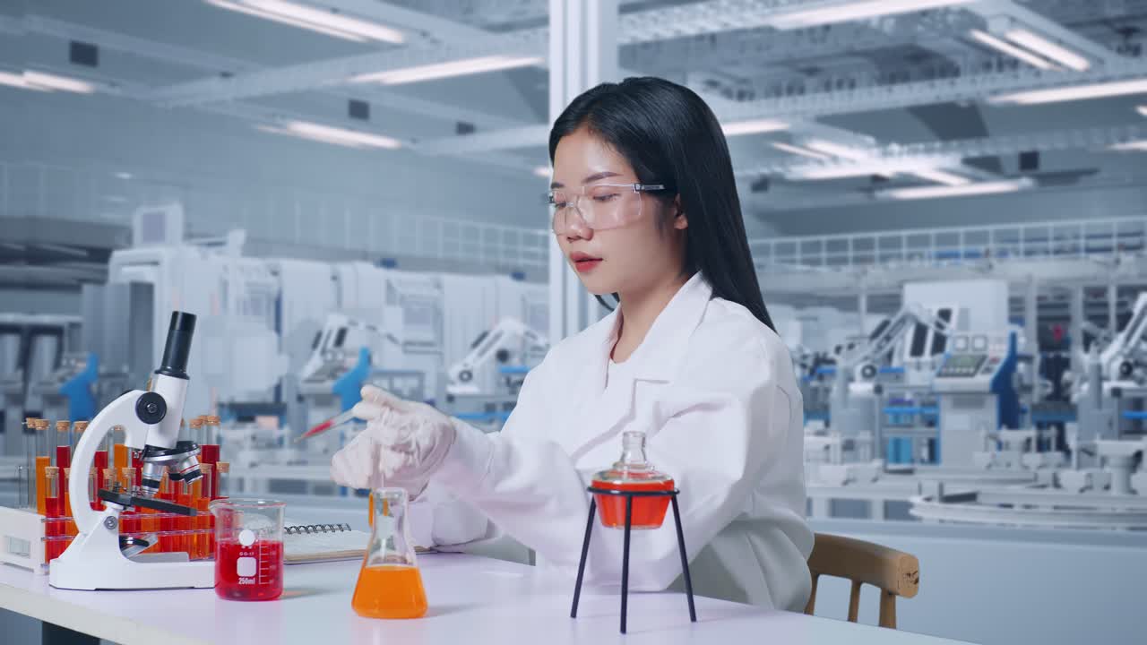 Side View Of Asian Woman Scientist Making Experiment With Test Tube And Writing Into Notebook In The Laboratory With Microscope. Working In The Lab Analyzing Finding Sample Test Tube