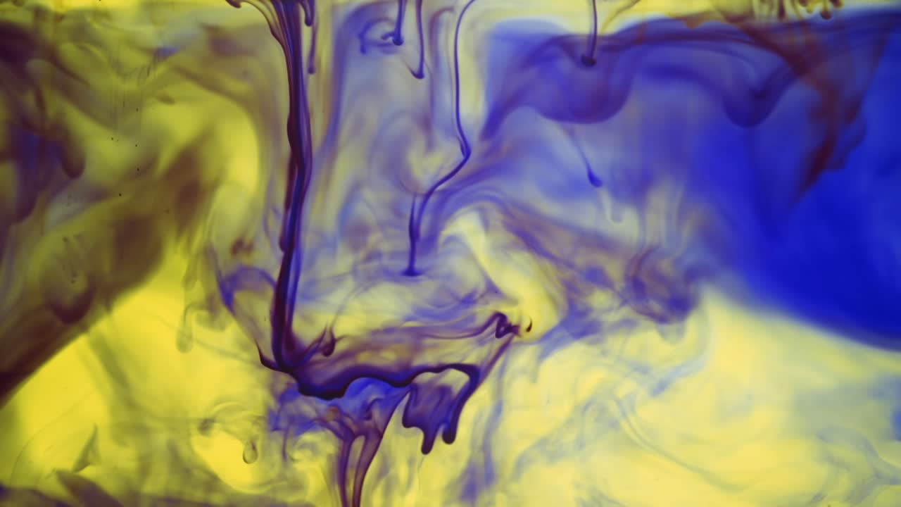 Colorful chemical liquids mix and swirl in water, forming smooth abstract patterns and organic shapes