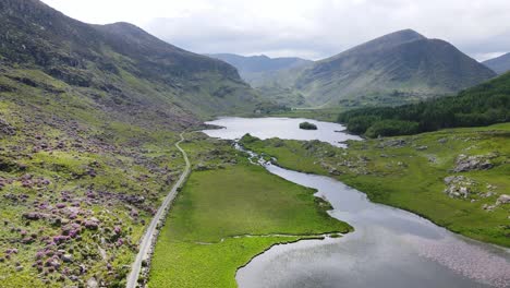 Eine-Luftaufnahme-Nach-Vorne-Entlang-Der-Straße-Und-Dem-Fluss-In-Richtung-Der-Berge