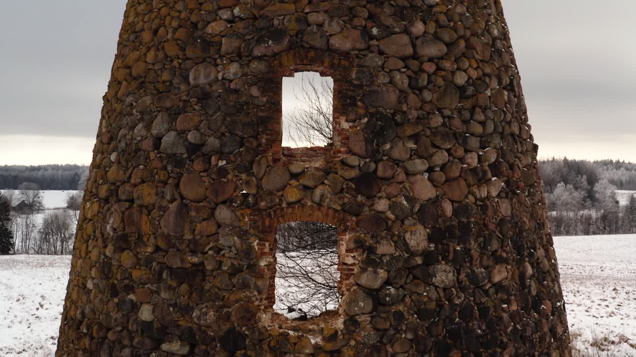 Aerial close up of abandoned historic windmill ruins with sun rays breaching through.